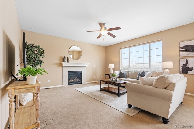 carpeted living room featuring a tiled fireplace and ceiling fan