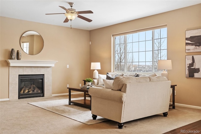 living room with ceiling fan, carpet, and a tile fireplace