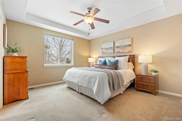 carpeted bedroom with a raised ceiling and ceiling fan