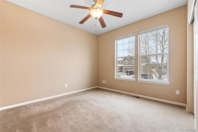 empty room with plenty of natural light, light colored carpet, and ceiling fan