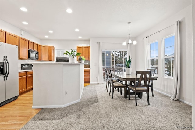 kitchen featuring light carpet, white refrigerator with ice dispenser, a chandelier, a center island, and hanging light fixtures