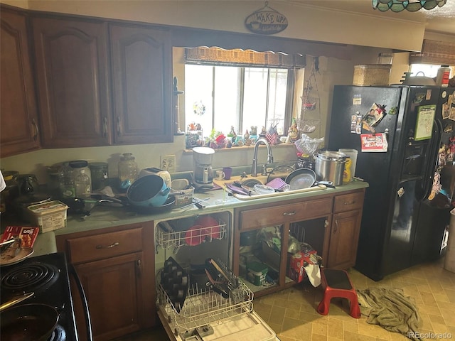 kitchen featuring sink, black refrigerator with ice dispenser, and light tile floors