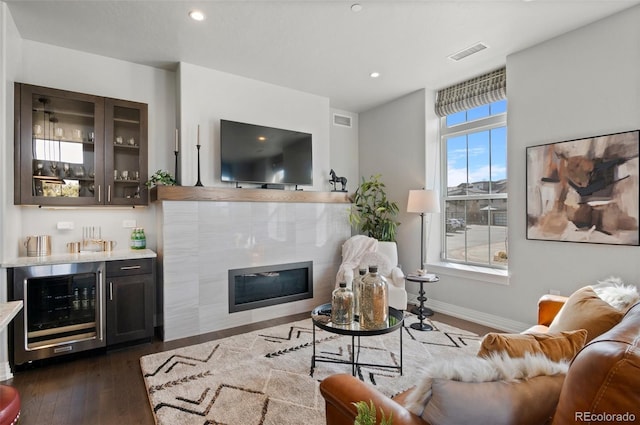 living room featuring wet bar, beverage cooler, visible vents, and dark wood-style flooring