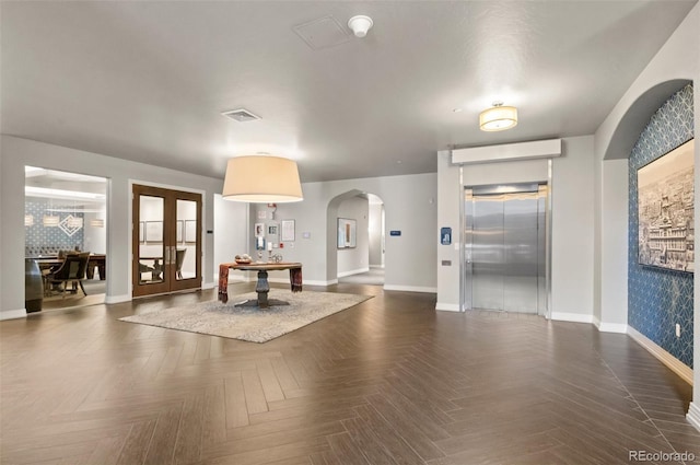 interior space with visible vents, baseboards, elevator, arched walkways, and french doors