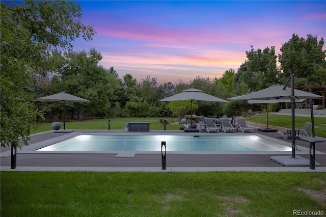 pool at dusk with a yard and a patio area