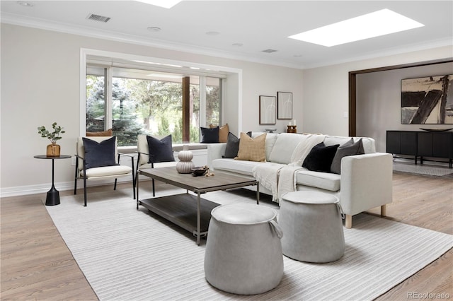 living room with ornamental molding, light wood-type flooring, and a skylight