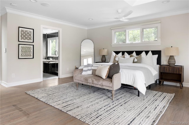 bedroom featuring ceiling fan, ensuite bath, ornamental molding, and hardwood / wood-style flooring