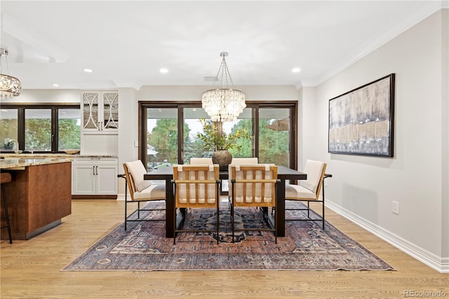 dining space featuring light hardwood / wood-style floors, ornamental molding, a chandelier, and a healthy amount of sunlight