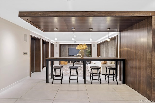 bar with light tile patterned floors, a tray ceiling, and elevator