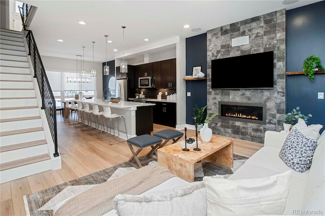 living room with stairs, a fireplace, light wood-style flooring, and recessed lighting