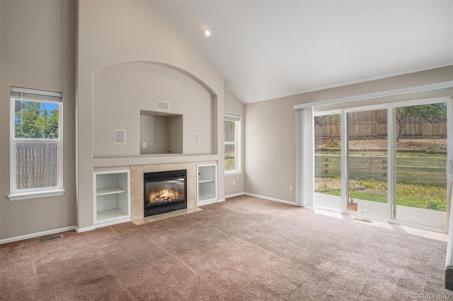 5755 S Zante Cir, Aurora, CO 80015 - unfurnished living room featuring carpet, healthy amount of natural light, high vaulted ceiling, and a tiled fireplace
