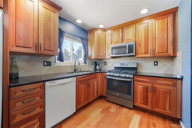 kitchen with backsplash, sink, light wood-type flooring, and stainless steel appliances