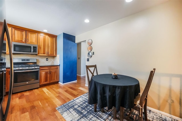 kitchen featuring decorative backsplash, light hardwood / wood-style flooring, and appliances with stainless steel finishes