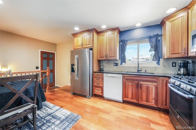 kitchen featuring decorative backsplash, sink, light hardwood / wood-style flooring, and appliances with stainless steel finishes