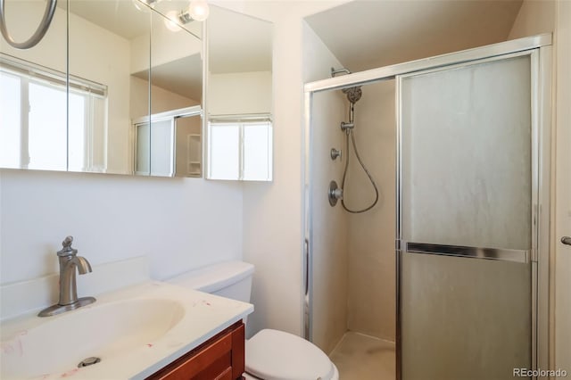 bathroom with vanity, toilet, and a shower with door