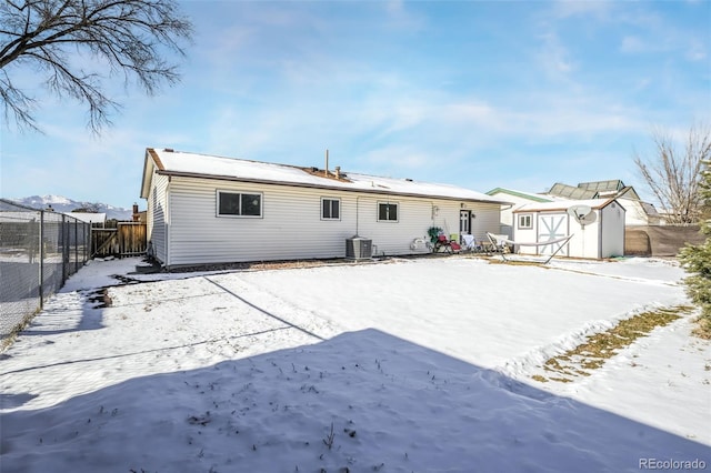 snow covered rear of property with a storage shed and central air condition unit