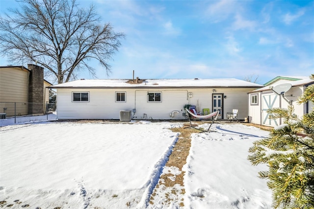 snow covered property featuring central AC and a storage shed