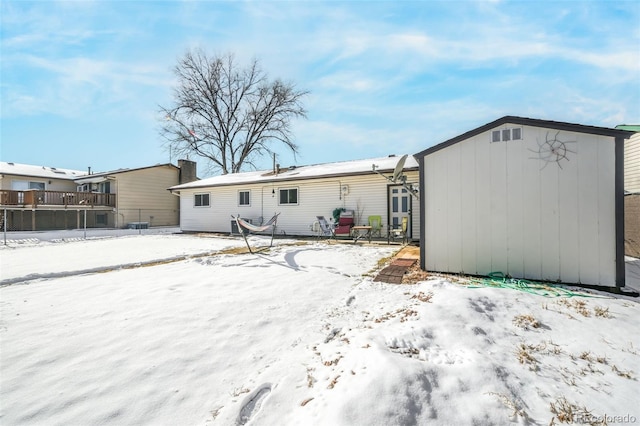 snow covered house featuring a storage shed