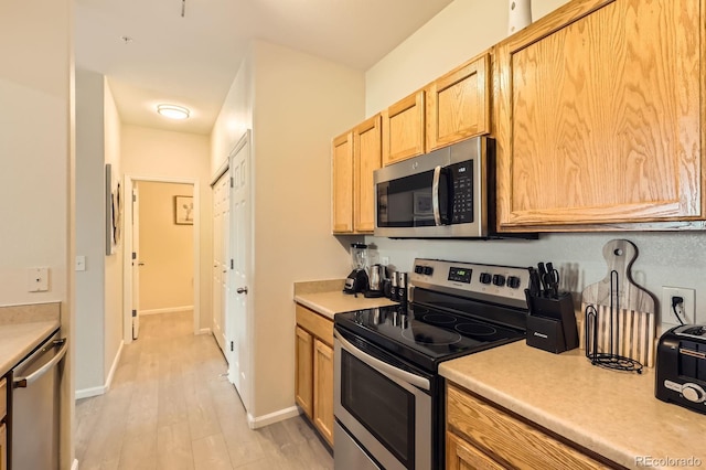 5255 Memphis St Unit 311, Denver, CO 80239 - kitchen featuring stainless steel appliances, light countertops, light wood-style flooring, light brown cabinets, and baseboards