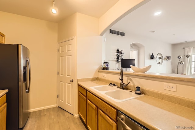 5255 Memphis St Unit 311, Denver, CO 80239 - kitchen featuring stainless steel appliances, a sink, light wood-style floors, brown cabinetry, and arched walkways