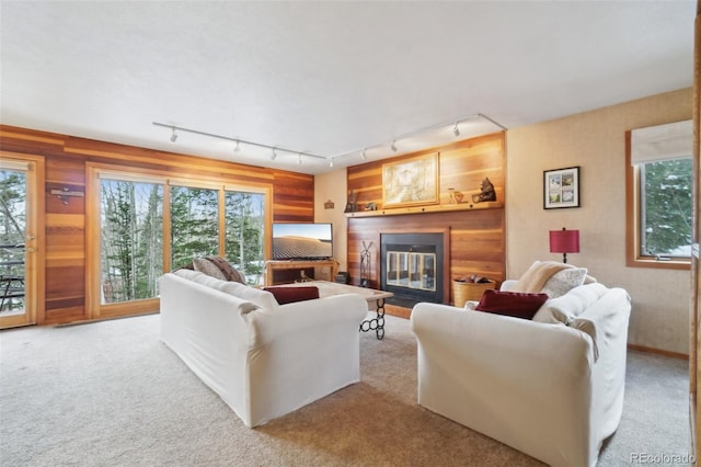 carpeted living area featuring track lighting and a glass covered fireplace