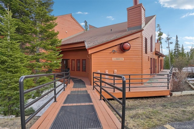 rear view of property featuring a chimney and a deck