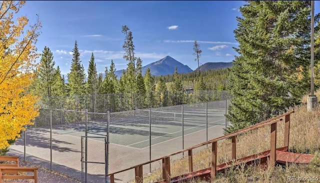 view of tennis court with fence and a mountain view