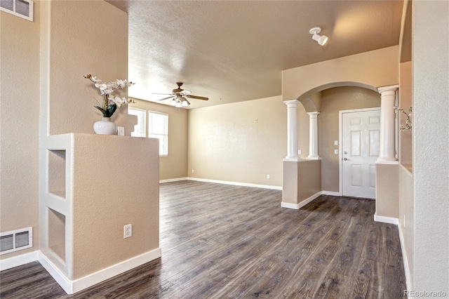 empty room with ornate columns, ceiling fan, and dark hardwood / wood-style flooring