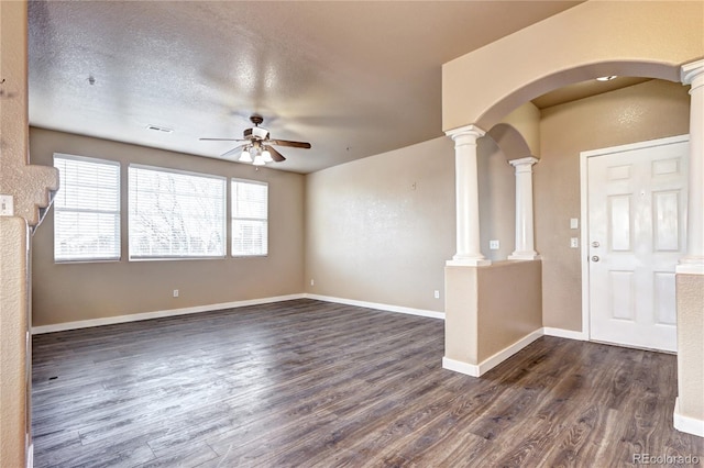 unfurnished living room featuring a textured ceiling, decorative columns, dark hardwood / wood-style floors, and ceiling fan