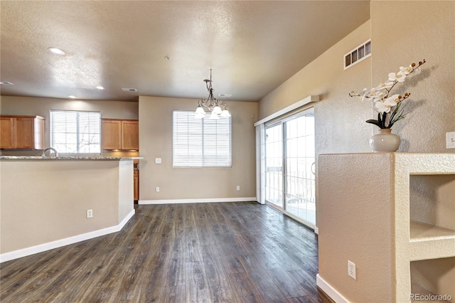 kitchen with dark wood-type flooring, pendant lighting, a textured ceiling, and a chandelier