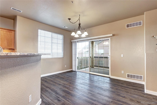 unfurnished dining area with dark wood-type flooring and a notable chandelier