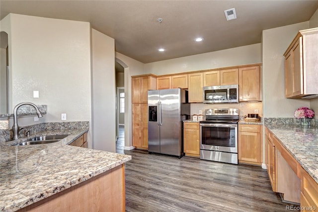 kitchen featuring appliances with stainless steel finishes, dark hardwood / wood-style floors, light brown cabinetry, sink, and light stone countertops