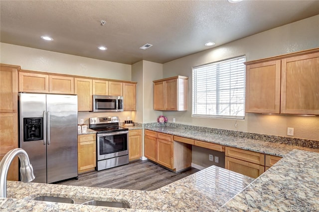 kitchen with stainless steel appliances, sink, a textured ceiling, and light stone counters