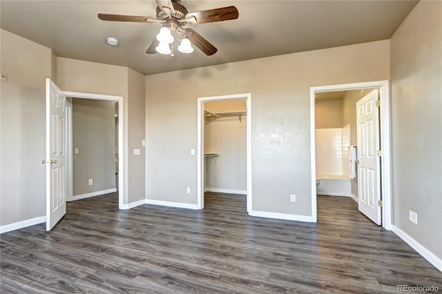 unfurnished bedroom with a spacious closet, dark wood-type flooring, ceiling fan, and ensuite bathroom