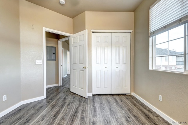 unfurnished bedroom featuring dark wood-type flooring, electric panel, and a closet