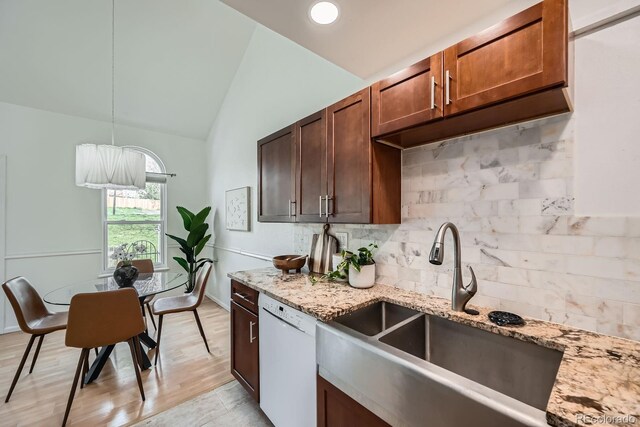 494 Owl Dr Unit 4, Louisville, CO 80027 - kitchen with white dishwasher, a sink, decorative backsplash, vaulted ceiling, and light stone counters