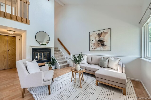 494 Owl Dr Unit 4, Louisville, CO 80027 - living area with high vaulted ceiling, light wood-type flooring, stairway, a glass covered fireplace, and baseboards