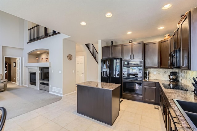 3490 Craftsbury Dr, Highlands Ranch, CO 80126 - kitchen with black appliances, dark brown cabinetry, light colored carpet, a center island, and light stone counters