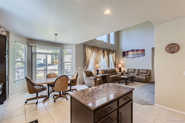 3490 Craftsbury Dr, Highlands Ranch, CO 80126 - kitchen with a textured ceiling, stone counters, dark brown cabinets, light tile patterned floors, and a center island