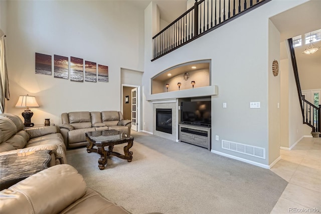 3490 Craftsbury Dr, Highlands Ranch, CO 80126 - tiled living room with a towering ceiling, stairway, a glass covered fireplace, and carpet floors