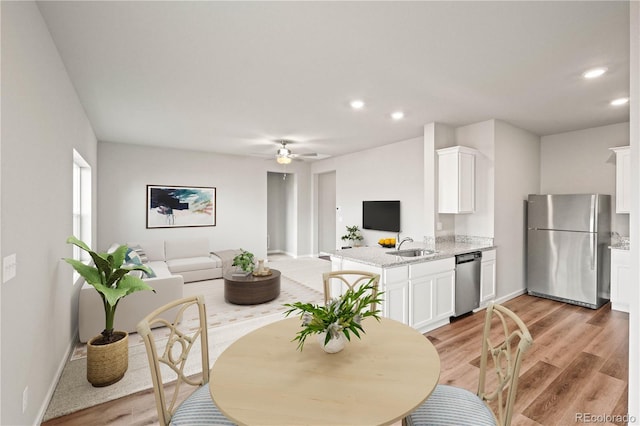 dining space with ceiling fan, light wood-type flooring, and sink