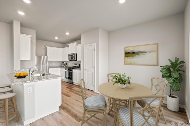 kitchen featuring sink, stainless steel appliances, light stone counters, kitchen peninsula, and white cabinets