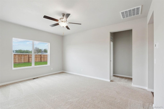 empty room with ceiling fan and light carpet