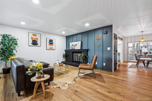 living room featuring a brick fireplace and hardwood / wood-style flooring