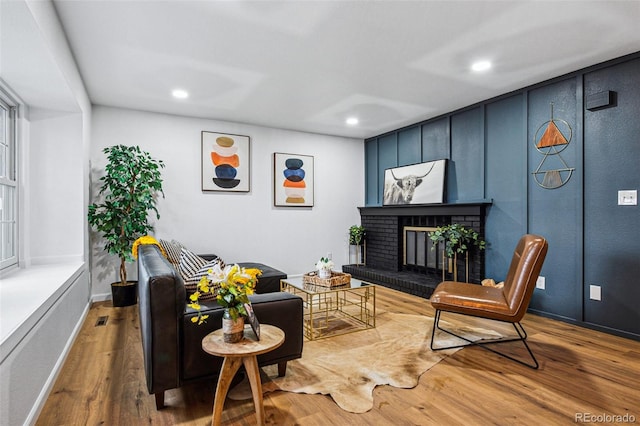 living room with a brick fireplace and hardwood / wood-style flooring