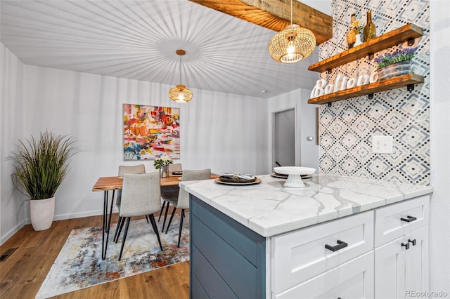 kitchen featuring dark wood-type flooring, white cabinets, light stone counters, and decorative light fixtures