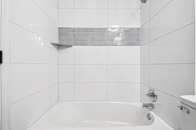 bathroom featuring toilet and tiled shower / bath