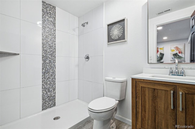 bathroom with vanity, toilet, and tiled shower