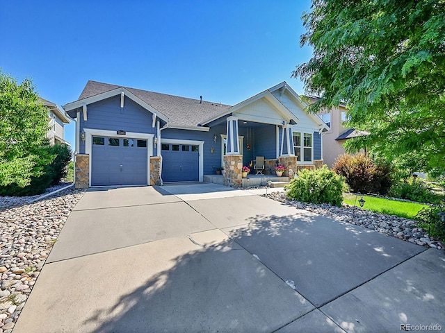 5309 W Hoover Dr, Littleton, CO 80123 - view of front facade with a porch, stone siding, driveway, an attached garage, and a shingled roof