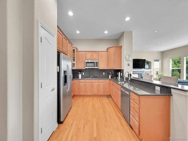 5309 W Hoover Dr, Littleton, CO 80123 - kitchen featuring appliances with stainless steel finishes, light wood-type flooring, a peninsula, decorative backsplash, and glass insert cabinets